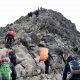 People climbing a mountain, the leaders have reached the top