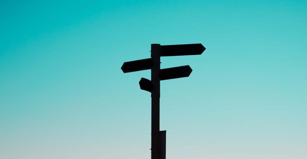Signpost silhouetted against a teal sky