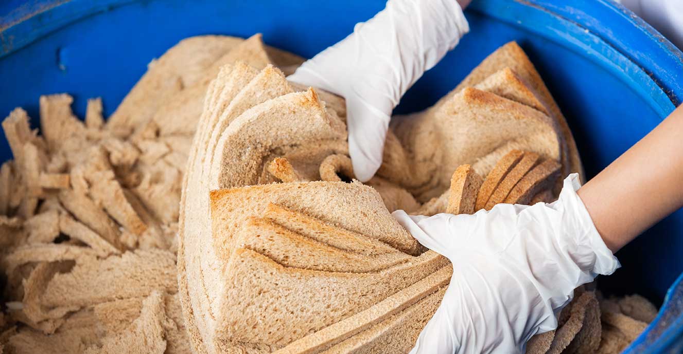 Bread waste being placed in a bin on a food production line.